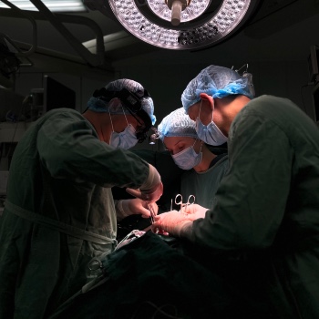 Photo of three people performing surgery