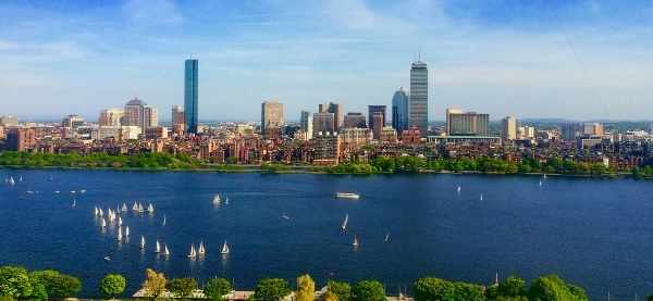 Photo of Boston skyline over river with sailboats