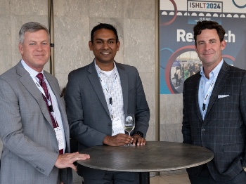 Three men standing at a table smiling